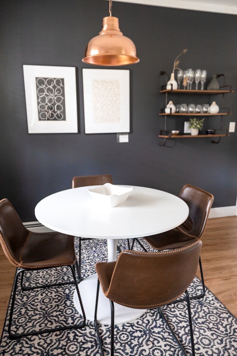 Contemporary dining room setup with brown chairs, white table, and copper pendant light.