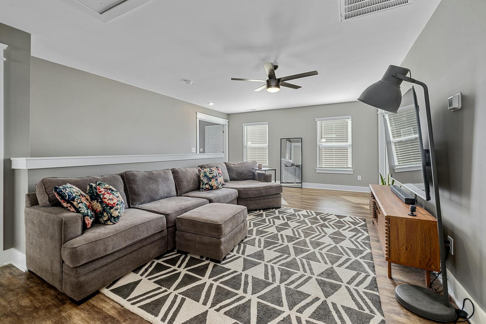 Cozy modern living room with a large sofa, TV, and stylish decor.