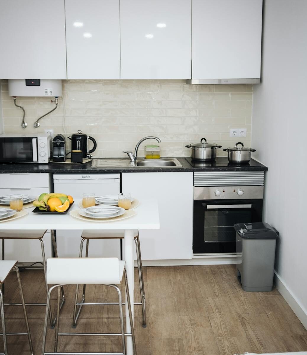 Contemporary white kitchen with modern appliances, dining table, and minimalistic decor.