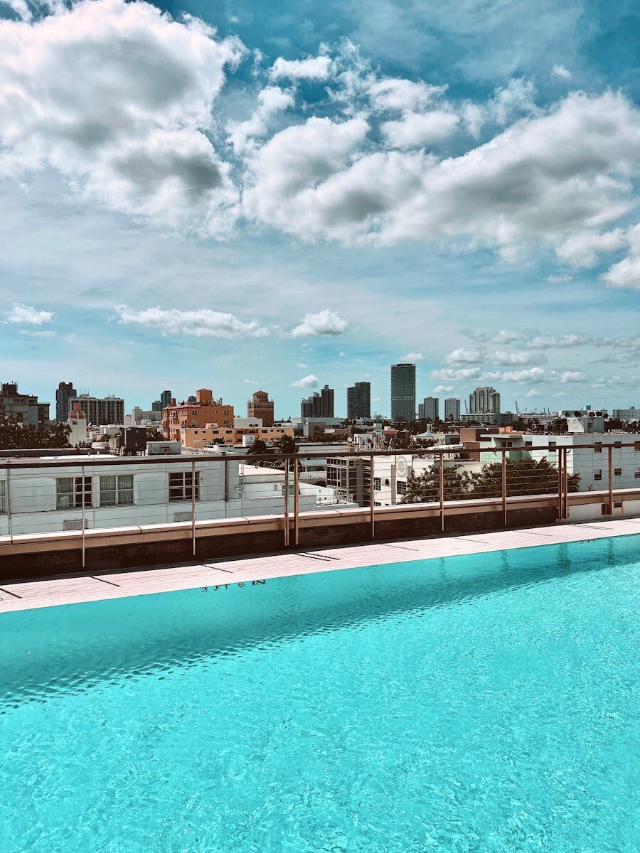 A rooftop pool with a stunning city skyline view under a blue sky.