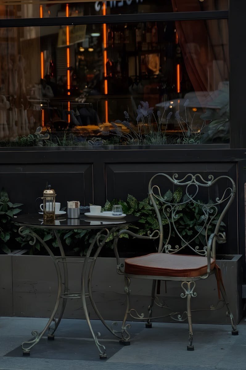 A quaint outdoor café scene with a vintage chair and table ready for a coffee break.