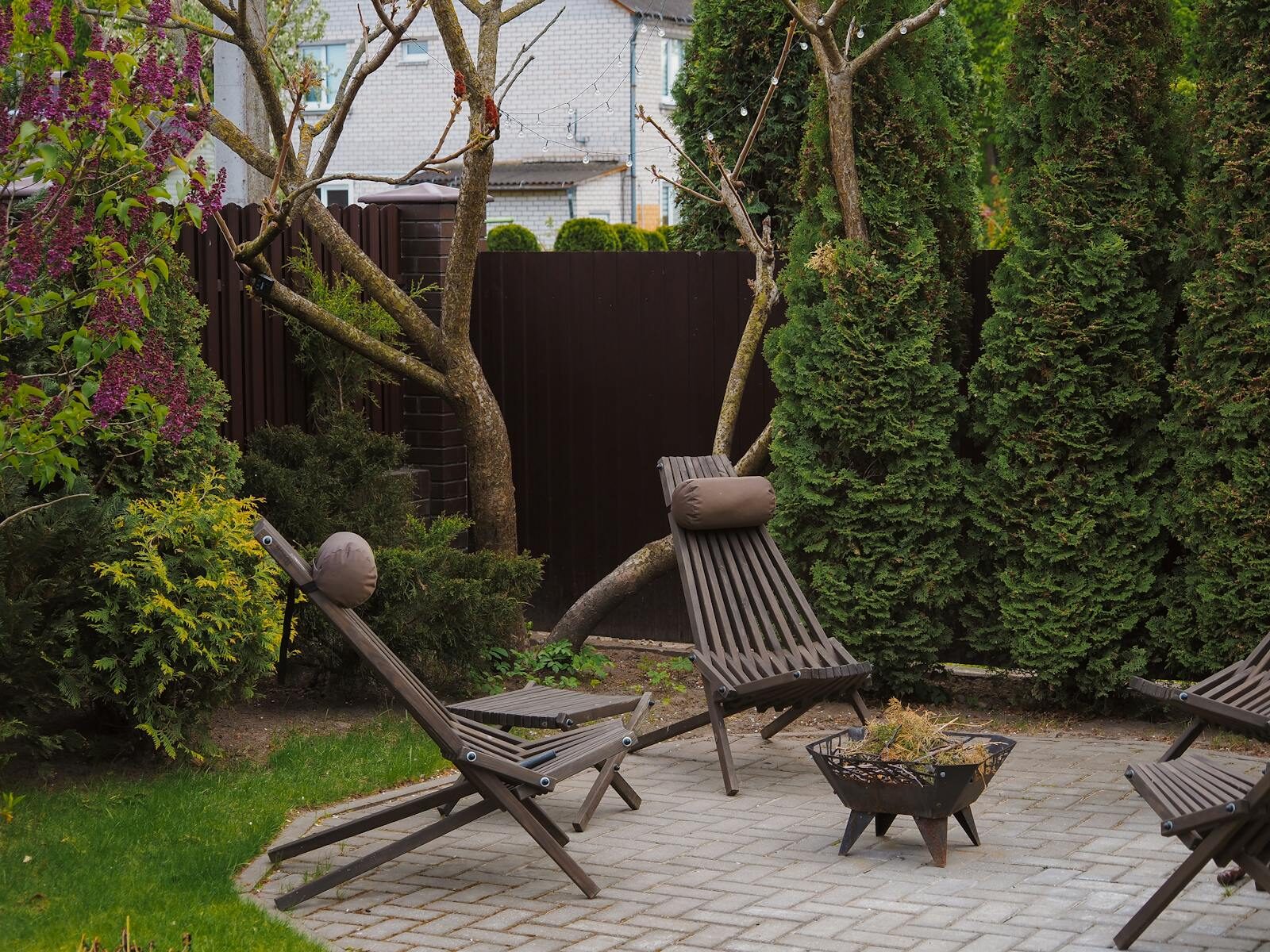 Cozy backyard featuring wooden lounge chairs and lush greenery, perfect for relaxation.