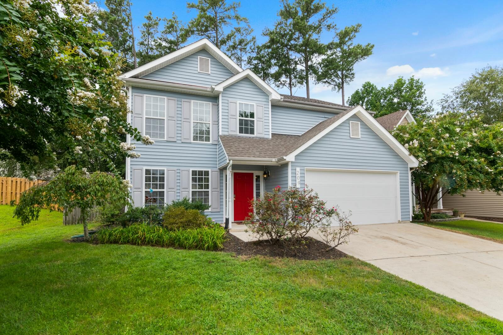 Charming suburban two-story house with a well-maintained lawn and vibrant garden.