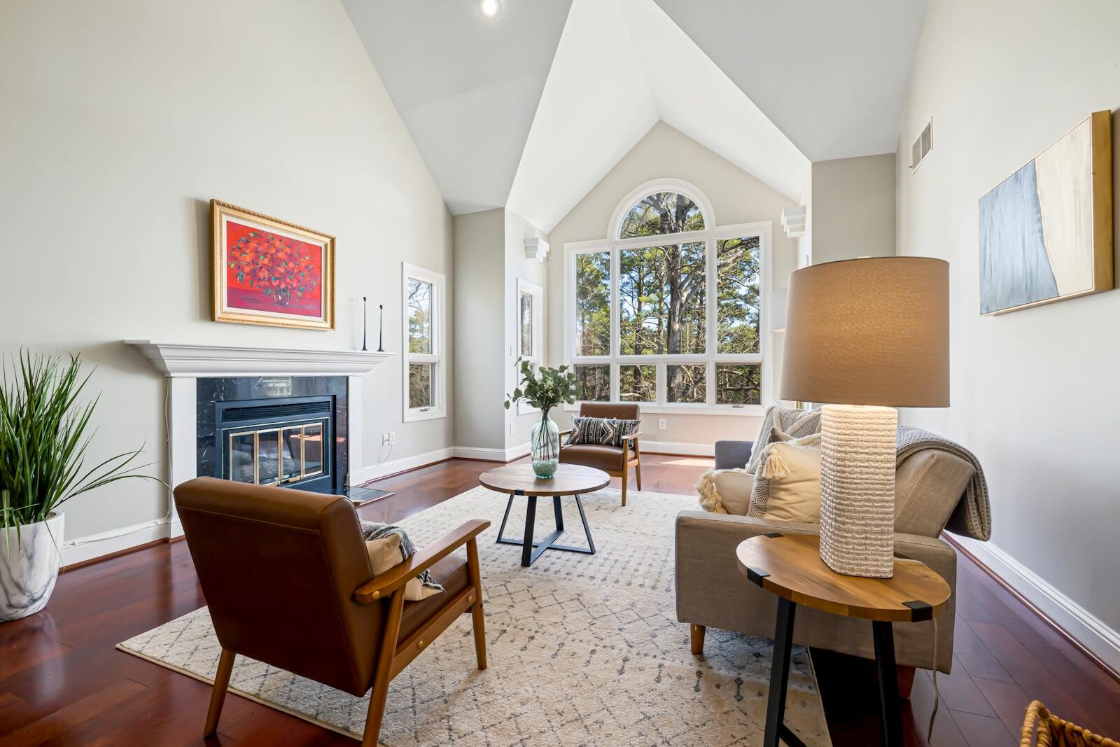 Elegant modern living room featuring a fireplace, high ceilings, and large windows.