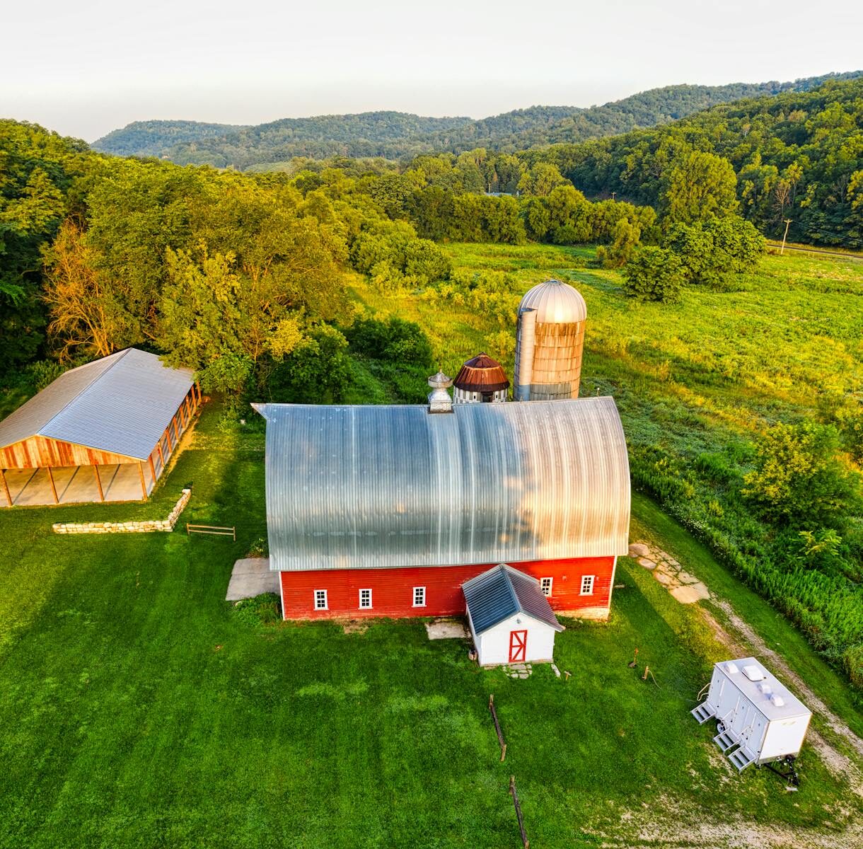A scenic aerial photograph showcasing a picturesque red barn amidst lush green fields in rural Minnesota.
