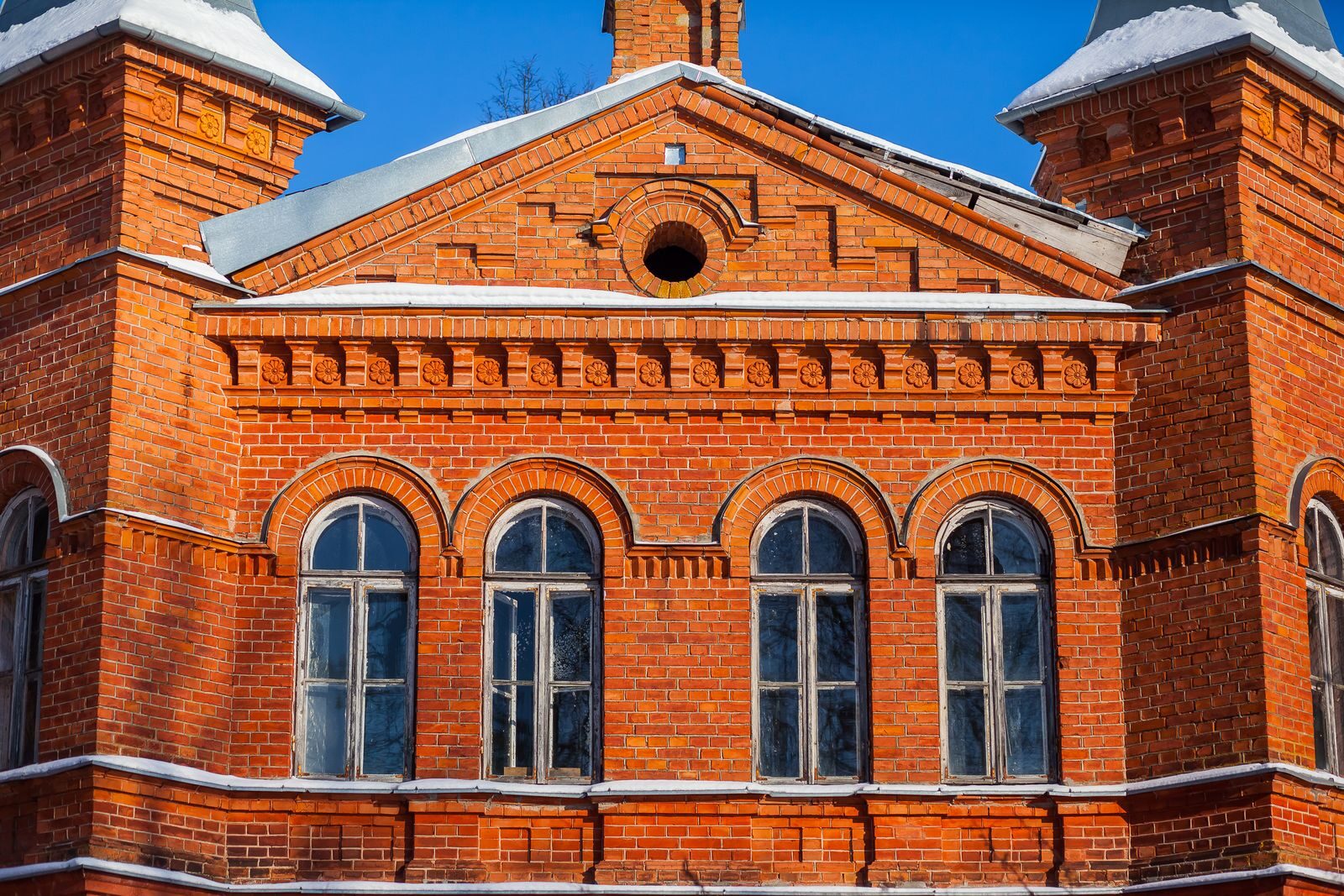 Vibrant red brick architecture of a historic building in winter, showcasing classic design elements under bright blue skies.