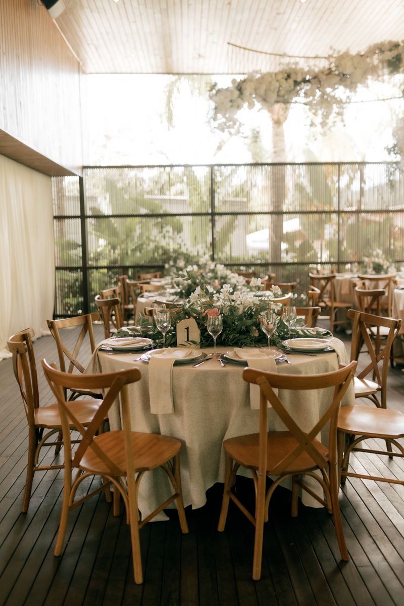 Beautifully arranged wedding reception table with floral centerpiece and wooden chairs.