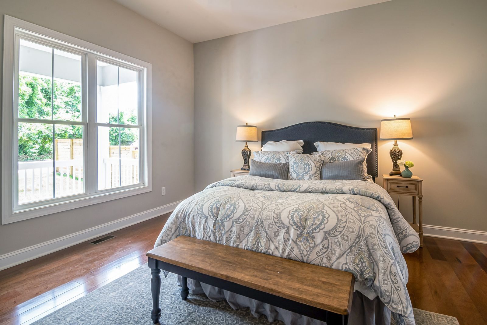 Bright and elegant bedroom featuring a cozy bed, night tables, and soft lighting.