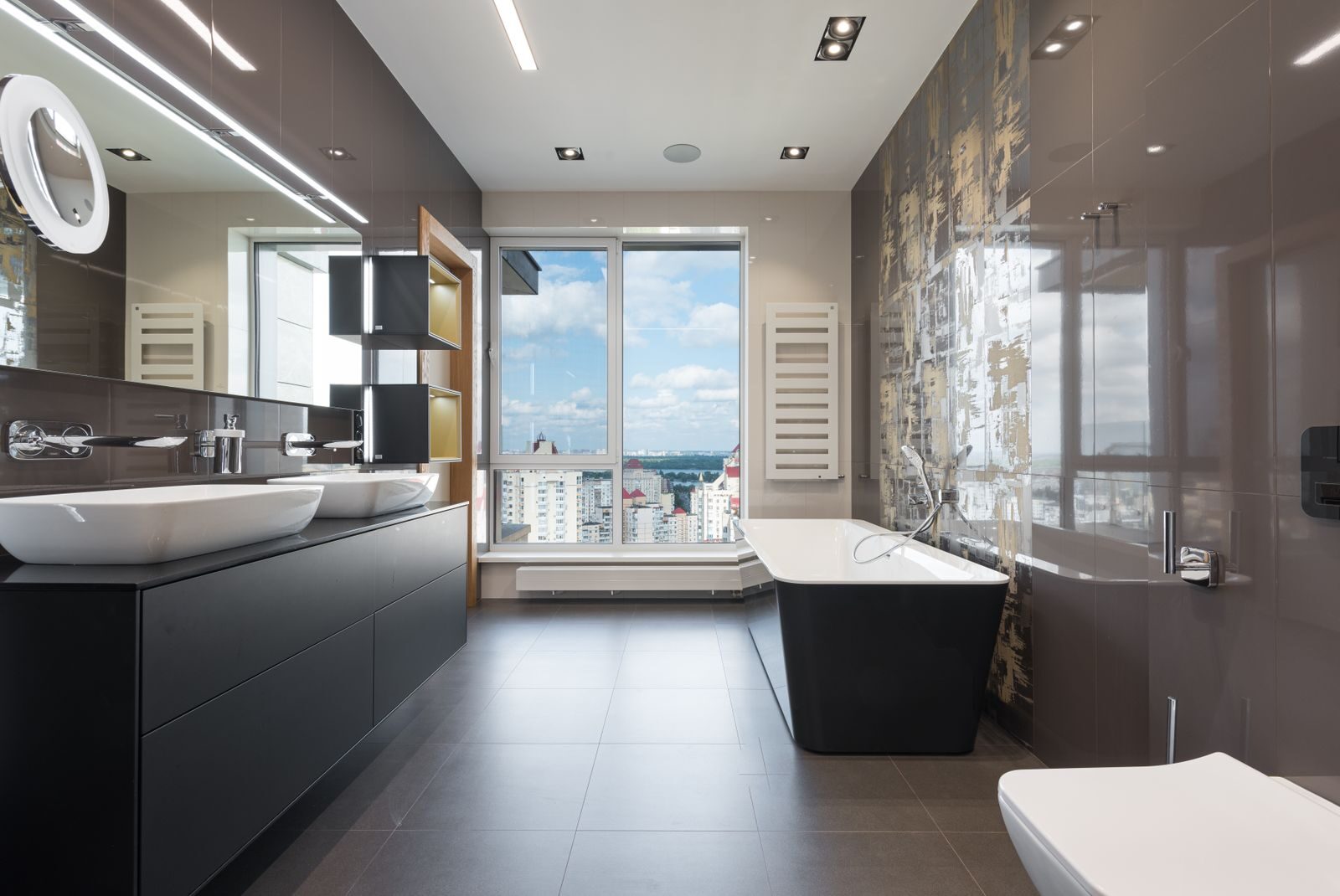 Wooden furniture with bathtub and ceramic sinks and toilet bowl in contemporary master bathroom with big windows in daylight