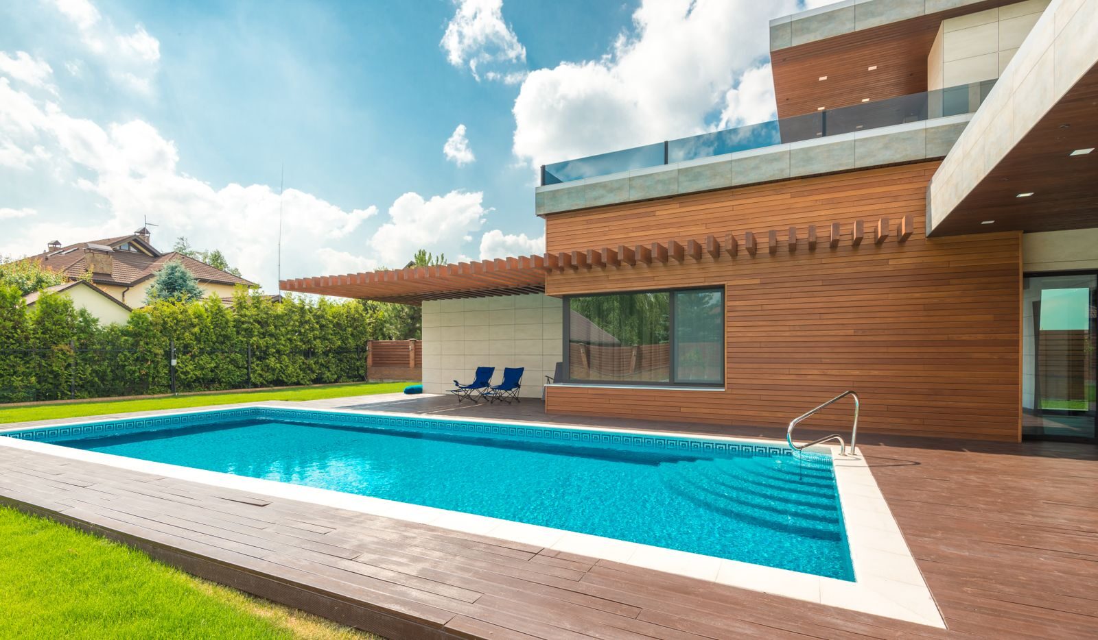 Spacious backyard with a modern house and swimming pool under a clear blue sky.