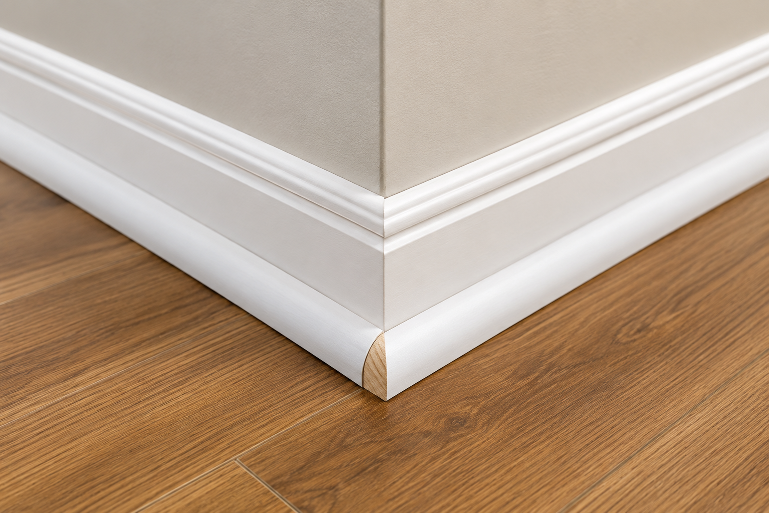Quarter round molding installed along a white baseboard with hardwood flooring, showcasing a clean interior trim finish for modern home renovation and flooring projects.