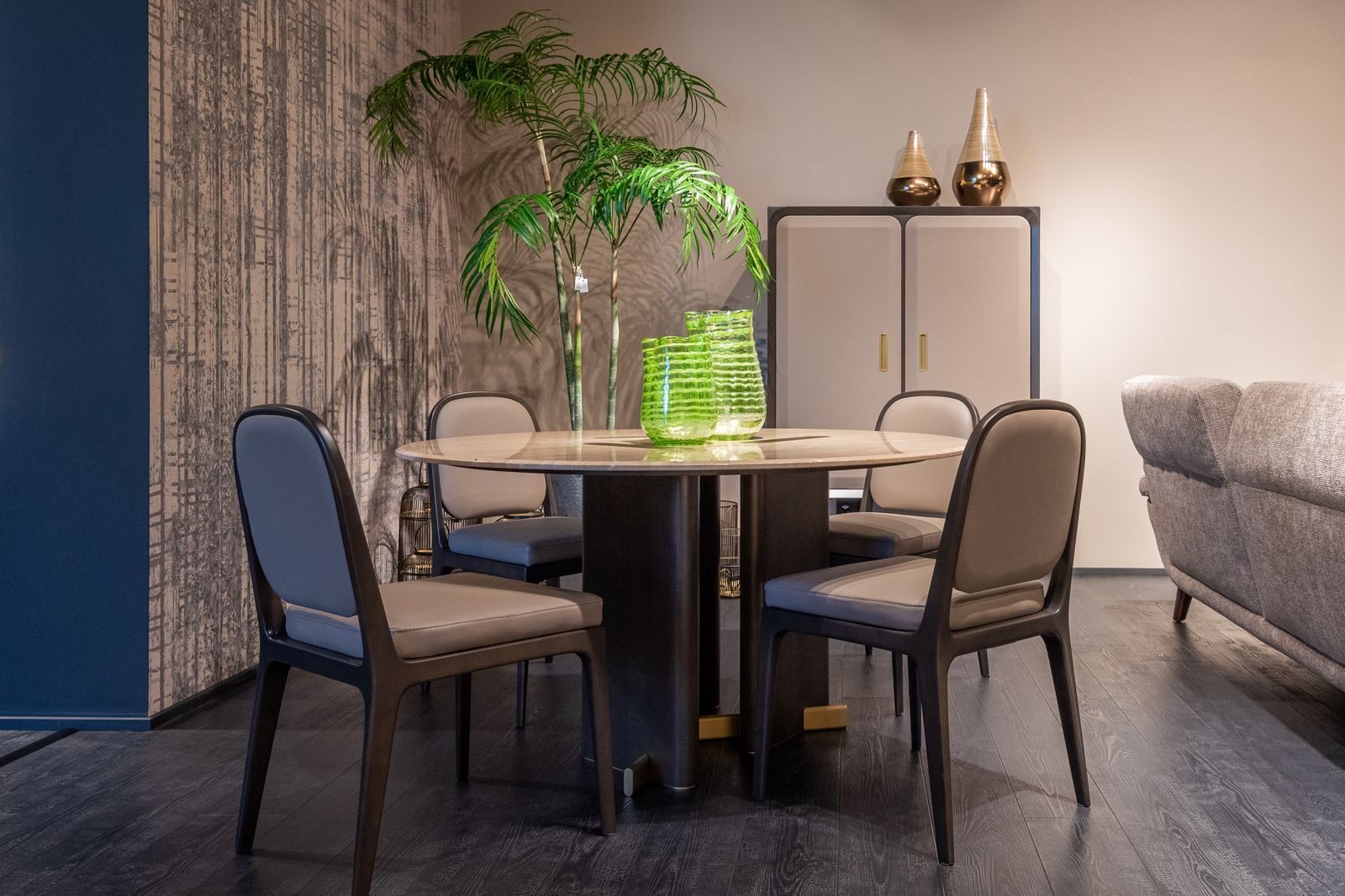 Trendy interior design of modern dining room with cozy chairs and round table decorated with stylish green vases