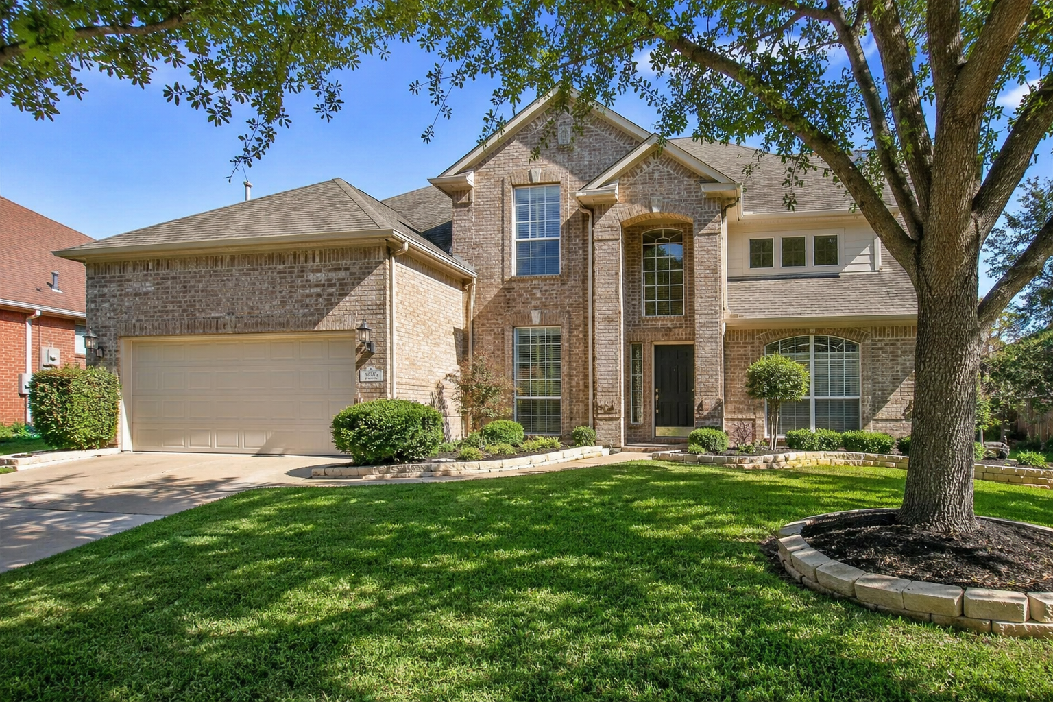 Front exterior of a spacious two-story brick home at 2005 Clubview Dr, Carrollton, TX 75006, featuring a landscaped front yard, attached garage, and manicured lawn in a quiet suburban neighborhood.