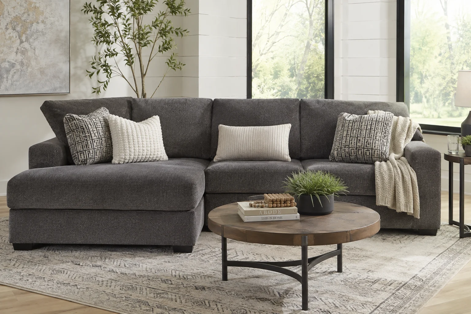Ashley Aviemore 2-Piece Sectional with Chaise in a modern living room with decorative pillows and a round coffee table.