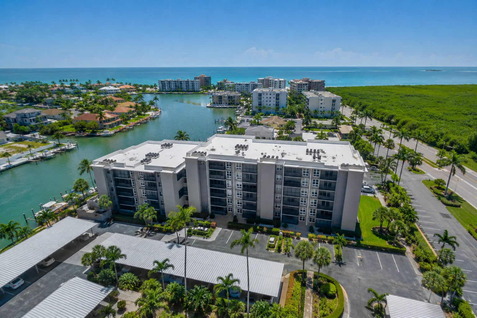 Aerial view of a waterfront condominium property near 440 Seaview Ct APT 409 in Marco Island, Florida, surrounded by canals, palm trees, coastal homes, and ocean views.