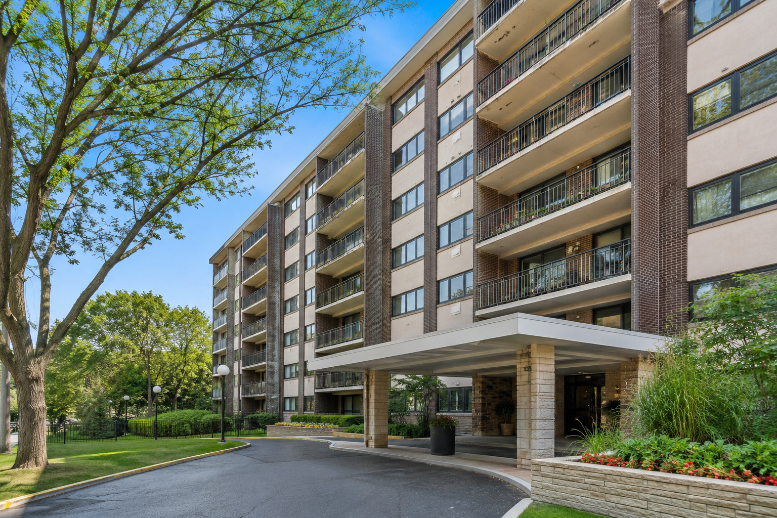 Modern exterior view of Pavilion Apartments at 5441 N East River Rd in Chicago, IL, featuring landscaped grounds, private balconies, and a covered residential entrance on a sunny day.