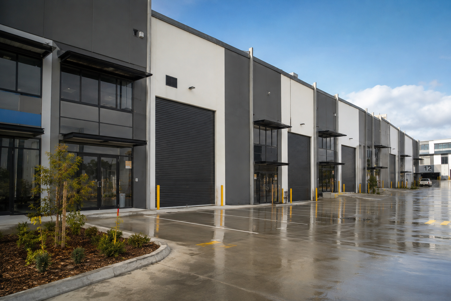 Modern industrial units for sale at 2 Transport Street, Yatala featuring contemporary warehouse buildings with roller doors, office spaces, and spacious concrete access area under a clear blue sky.
