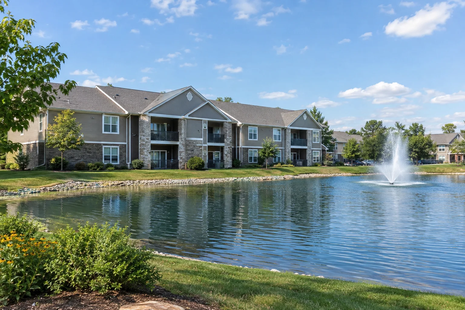 Two-story apartment building at The Ponds on G E Road in Bloomington, IL, with an on-site pond and fountain.