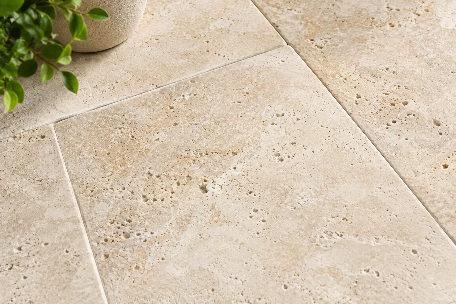 Close-up of honed ivory travertine tile showing natural stone texture and pitting.