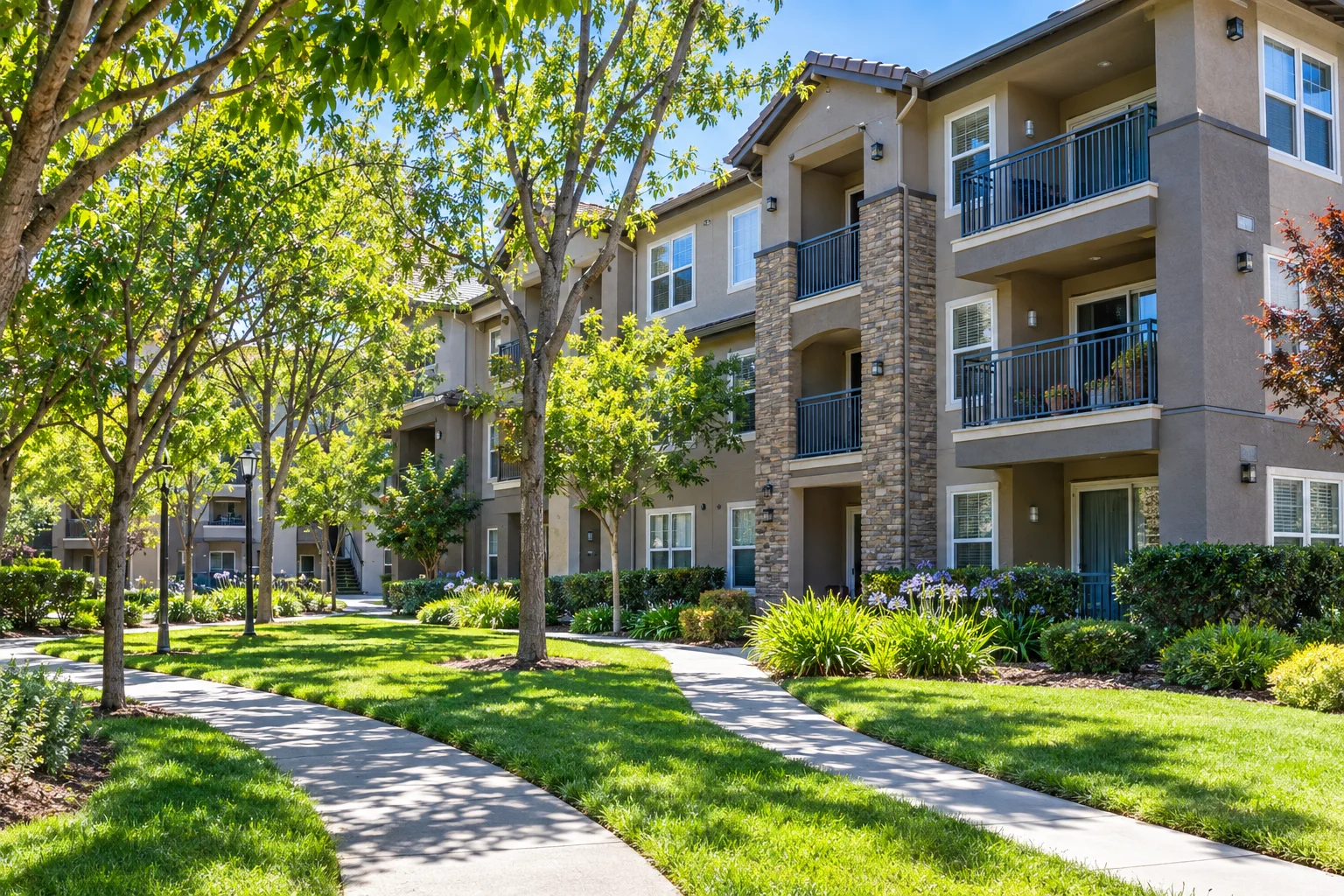 Three-story apartment building with tree-lined walkways and grassy areas in San Jose